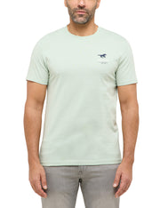 Tricou Austin verde deschis, față, purtat pe model, siglă mică pe piept cu cal alergând și textul „Mustang”