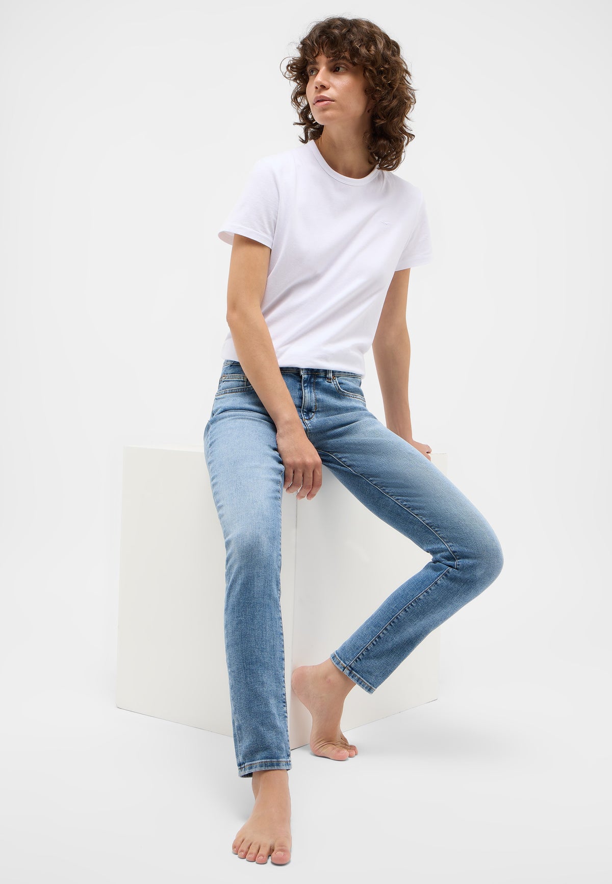Blugi Skinny Quincy albastru, lateral, purtați de model așezat, croi mulat pe picior