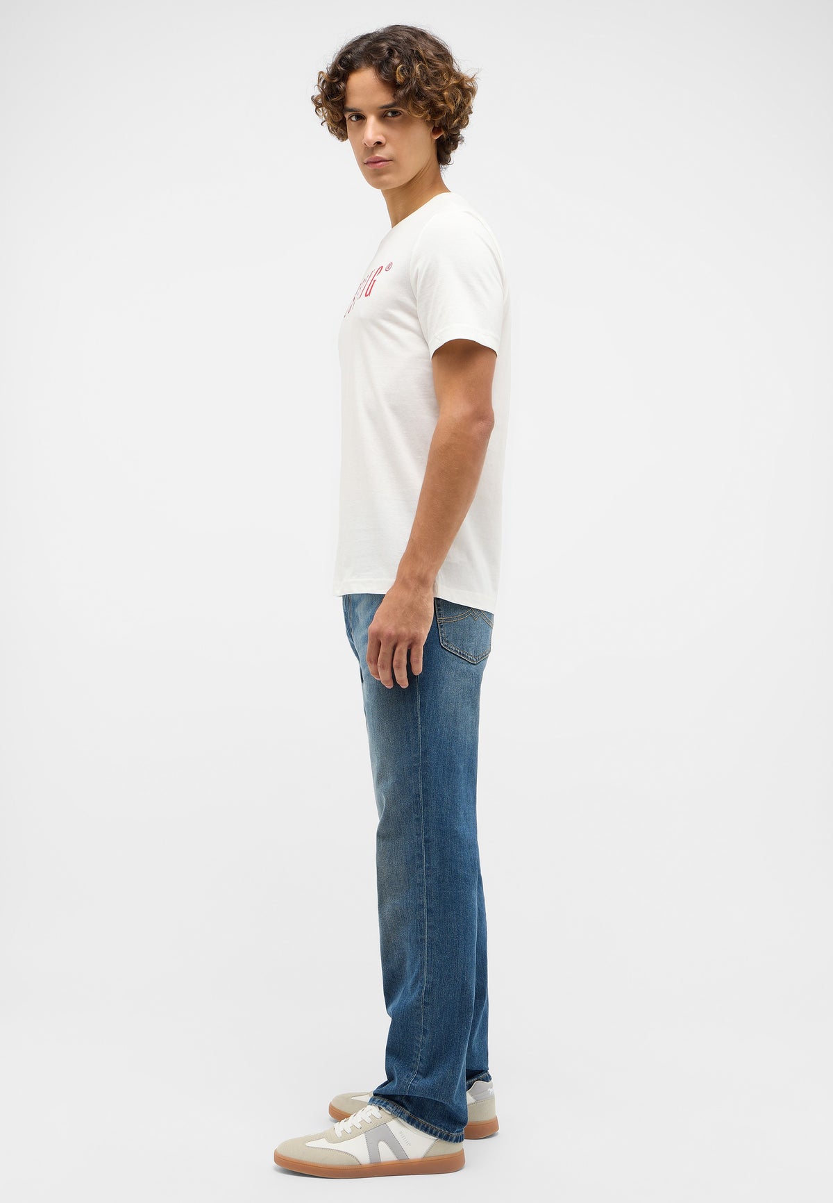 Tricou Austin alb, lateral, imprimeu roșu vizibil parțial, purtat cu blugi și pantofi sport